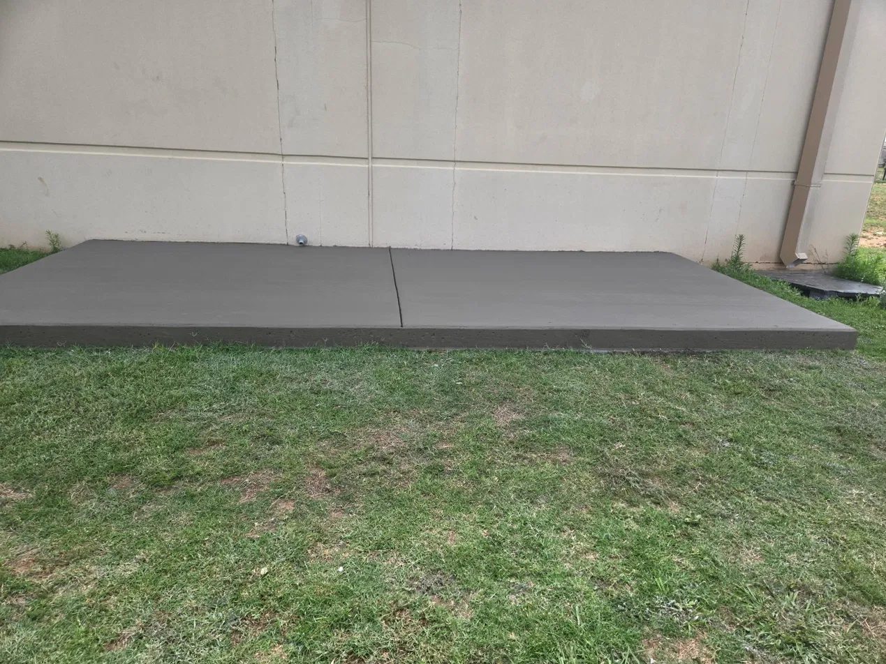 New concrete slab with a control joint poured against the wall of a commercial building