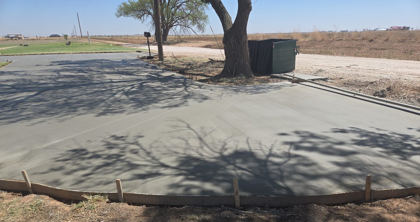 Large new driveway with a curved edge, still in its forms, at a rural home near Idalou
